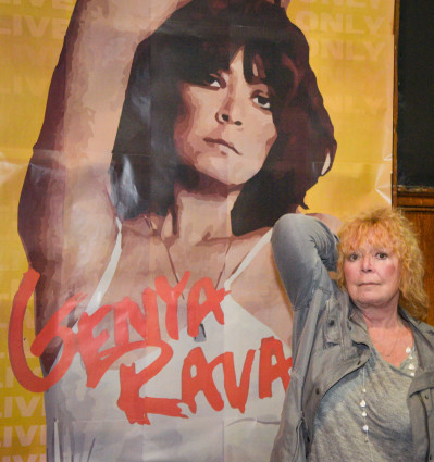 Genya Ravan poses in front of a painting of herself